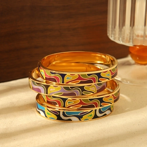 Detail showing colorful enamel stacked bracelets with golden finish on fabric