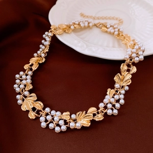 Detail view of vintage gold leaf necklace with pearls on a white ceramic plate