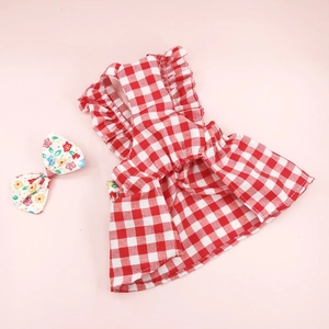 Detailed close-up of red and white plaid pet dress with floral bow accessory