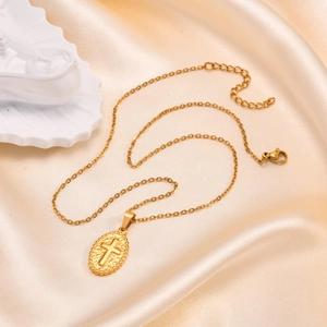 Vintage golden necklace with oval cross pendant on champagne silk background