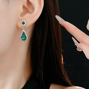 Macro view of crystal teardrop earring with green stone and silver flower detail