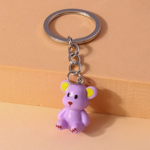 Close-up of a purple resin bear keychain with silver metal ring on a textured surface