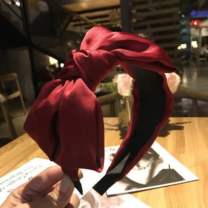 Close-up of a dark red satin headband with a vintage knotted bow design for women
