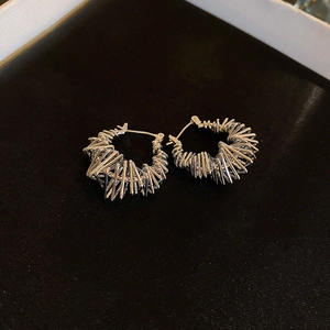 Macro view of silver bird nest style irregular geometric earrings on black velvet