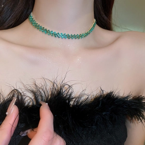 Dettaglio della collana girocollo con zircone verde e catena a maglia dorata sul collo