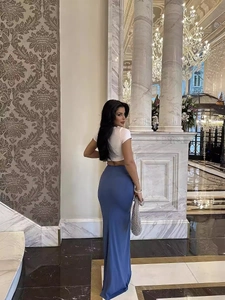 Elegant high-waisted blue slit maxi skirt paired with a white crop top in a luxury hall