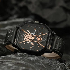 Detail of square black quartz watch with rose gold hands on dark rock background