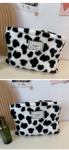 Detail view of plush cow print makeup pouch featuring a Time to Party label and top zipper