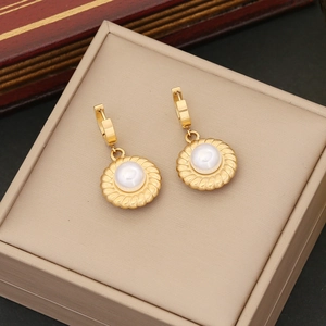 Elegant gold pearl earrings set in round textured base on a beige jewelry display box