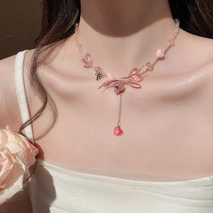 Detail of pink resin beaded necklace featuring a bow and heart pendant on a model
