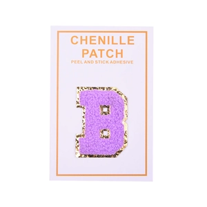 Macro detail of purple chenille letter B patch with golden glitter border and peel stick back
