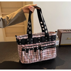 Pink plaid canvas tote bag detail showing punk rivets, metal eyelets and utility pockets