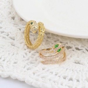 Eleganti anelli a serpente in oro con zirconi bianchi e occhi verdi su tessuto bianco
