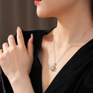 Close-up of light blue zircon rose pendant necklace worn on a model in soft lighting