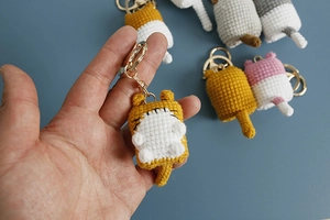 Close-up of handmade crochet yellow and white cat keychain with metal ring