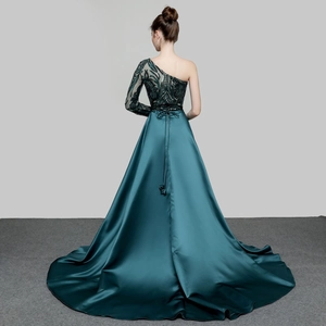 Detail of the back of a sequined emerald one-shoulder evening gown with a satin train