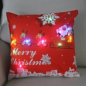 Detail of LED Christmas pillow showing glowing lights and Santa Claus on a beige sofa