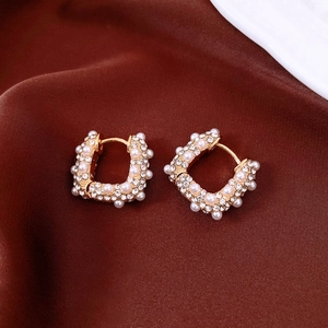 Vue macro de boucles d'oreilles en U plaquées or 18 carats avec strass et perles