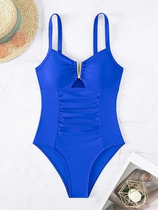 Detail of royal blue one-piece swimsuit with V-shaped gold hardware and ruched slimming fabric