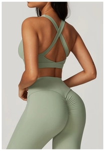 Dettaglio del reggiseno sportivo con schiena incrociata e leggings push-up verde salvia