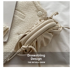 Detail shot of a cream-colored pleated cloud bag with an internal metal clip closure