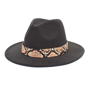 Détail d'un chapeau en laine noir avec bande en peau de serpent et rivet doré chic