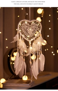 Close-up of white heart dream catcher with soft feathers and warm glowing LED lights