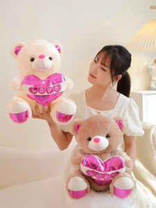 Detail of plush teddy bears in white and brown holding pink shiny LOVE hearts