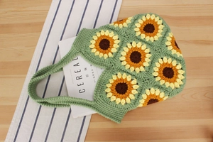 Detailed macro view of handmade crochet sunflower handbag with green knit texture