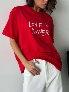 Detail of red cotton T-shirt featuring LOVE IS POWER graphic print and soft texture