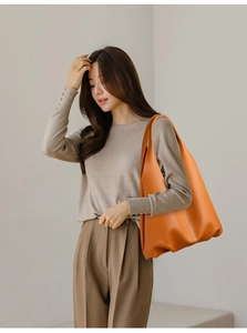Close-up of orange pebbled leather tote bag worn by a model for a stylish casual look