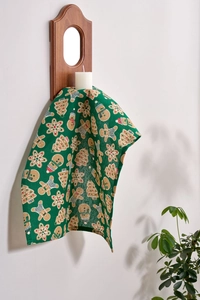 Detail of green linen napkin with gingerbread man and Christmas tree prints