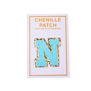 Detail of blue chenille letter N patch with gold sequins and peel and stick adhesive backing