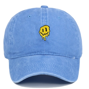 Détail de la broderie smiley jaune sur une casquette en coton délavé bleu clair