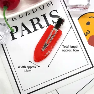 Detail of a 6cm red teardrop hair clip with a smooth glossy finish and metal duckbill clip