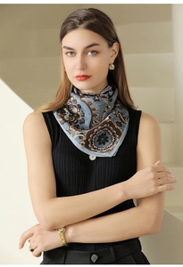 Close-up of floral paisley silk scarf with blue and gold patterns on a model