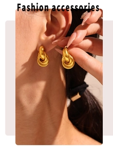 Detail of 18K gold plated ferris wheel knot earrings on model with warm lighting