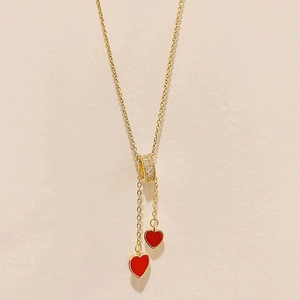 Detail of gold Y-shaped titanium steel necklace with a red heart shell pendant and tassel