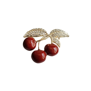 Élégante broche cerise en émail rouge avec feuilles dorées en cristal sur blanc