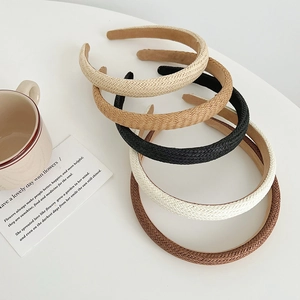 Handmade woven straw headbands in neutral colors displayed on a minimalist white desk