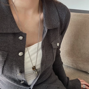 Detail view of retro long necklace with tiger eye and dalmatian stone on grey cardigan