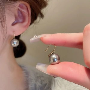 Détails d'une élégante boucle d'oreille en perle grise avec crochet doré sur modèle
