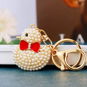 Detailed close-up of a luxury rhinestone duck keychain with cream pearls and a red bow