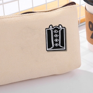 Creative alien totem enamel pin on beige canvas pouch with minimalist lifestyle backdrop