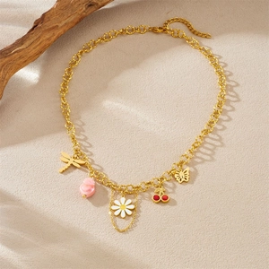 Golden chain necklace featuring daisy, cherry, and dragonfly charms on wooden background