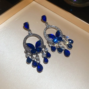 Detail of blue crystal butterfly tassel earrings with waterdrop charms on tray