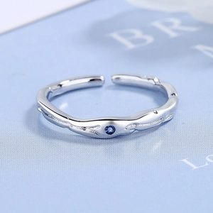 Bague vague argentée minimaliste avec zircon bleu sur fond bleu clair