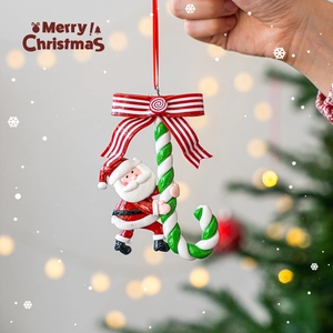 Christmas Santa climbing candy cane hanging ornament with festive warm background