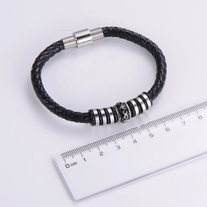Detail of black braided leather bracelet showing size measurement with a ruler