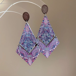 Detail of ethnic rhombic drop earrings with bohemian prints on a wooden base
